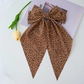 Detail of leopard print oversized bow hair clip with long streamers on a magazine - Coffee Leopard