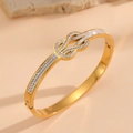 Detalle macro del brazalete infinito de oro de 18K con nácar e incrustaciones de cristal - Estilo de Nudo de Doble Anillo con Circona y Concha Dorada (H122)