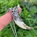 Men's retro wolf tooth pendant necklace with metallic totem held in natural light - White Wolf Tooth Style