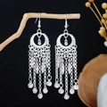 Macro shot of silver ethnic tassel earrings with bells hanging on a wooden stand - Bell Tassel (E4374-1) / Silver