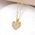 Dettaglio di una collana con ciondolo a cuore dorato con fiocco e pietre di zircone - Cuore