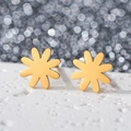 Close-up of gold-plated stainless steel daisy stud earrings on white stone stand - Daisy / Gold