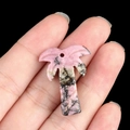 Pink and black spotted stone coconut tree pendant shown on finger with macro details - Rhodonite