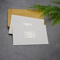 Close-up of white silver polishing cloth envelopes with gold foil text on wooden base - Silver Polishing Cloth Pouch
