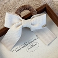 Details des Strick-Haargummis mit Schleife und Love is Forever Metallanhänger - Beige