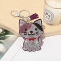 Sparkling rhinestone cat keychain with purple tassel and metal lobster clasp on tray - Purple