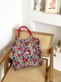 Borsa tote in tela a fiori con manici rossi su una sedia in vimini stile casual - Rame Retrò