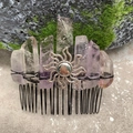 Detail of a handmade purple crystal hair comb with a sun motif on a mossy rock - Light Amethyst Black Wire Silver Sun