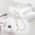 Close-up of handmade beaded phone strap with white beads and golden star pendant - White