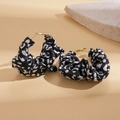 Close-up of C-shaped earrings wrapped in black and white leopard print fabric with gold studs - Black and White