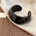 Macro detail of glossy black acrylic resin cuff bracelet with polished mirror surface - Black - Pleated Open