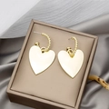 Detailed view of large gold heart drop earrings resting on silk fabric in a jewelry box - Gold Large Heart Dangle Earrings