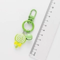 Lollipop keychain detail with ruler showing 8cm length and green bell decoration - Green