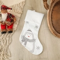 Kerstsok met witte pluchen rand en geborduurd pinguïnpatroon op een houten vloer - Pinguïnstijl