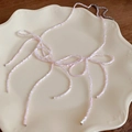 Pink beaded necklace styled in triple bow shapes on a vintage ceramic plate - Pink Beaded
