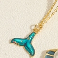 Macro-opname van walvisstaart hanger met groenblauwe druppelolie en glanzende lovertjes - Emaille Vissenstaart
