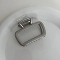 Dettaglio di una grande molletta per capelli in metallo argento su un piatto bianco - Grigio Argento - Grande Traforato