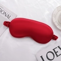 Red silk satin sleep mask with elastic strap on white textured bedding fabric - Burgundy