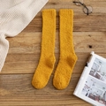 Yellow coral fleece knee-high socks on wooden table with cozy winter lifestyle accessories - Turmeric