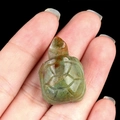 Hand-carved green crystal quartz turtle figurine displayed on palm for scale - India Agate