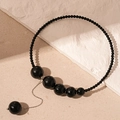Detalle del collar vintage con perlas negras y un elegante colgante de borla metálica - Collar de borlas de cuentas negras