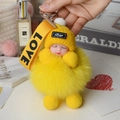 Detail of yellow sleeping baby doll keychain with plush fox fur pompom and love ribbon strap - Yellow