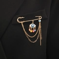 Goldene Sicherheitsnadel-Brosche mit Evil-Eye-Anhängern und Quasten an einem Blazer - Gold mit buntem Herz