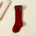 Dettaglio di calzino in maglia rossa per bambini con fiocco in nastro verde decorativo - XS (0-1 Anni) / Rosso