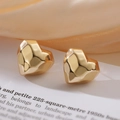 Detail of gold-plated heart stud earrings on elegant silk and vintage paper background - Gold Geometric Heart