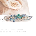 Eleganter Blumen-Haarclip mit blauen und grünen Steinen auf einem Magazin-Hintergrund - Pflaumenblüte - Blau