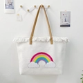 Detail of white woven tote bag with rainbow pattern, white tassels and brown leather handles - Rainbow