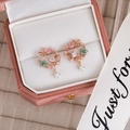 Primer plano de pendientes de flor y mariposa en oro rosa en una caja de regalo rosa - 27# Oro Rosa Mariposa Floral Hueco