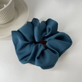 Detailed texture of a large dark teal satin hair scrunchie beside a ceramic cup - Navy Blue
