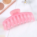Large pink plastic hair claw clip with glossy finish and curved teeth on white fabric - Jelly Pink