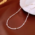 Detail of shell bead necklace with green stones on a silk fabric and ceramic plate - Necklace-White