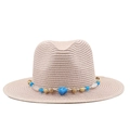 Detailed close-up of straw fedora with bohemian bead chain and natural shell accents - Pink