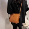 Minimalist caramel brown leather bucket bag shown on model with shoulder strap - Brown