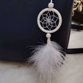 White dreamcatcher charm with soft feathers and beads hanging on a navy handbag - White
