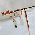 Golden hoop earrings with green natural quartz cylinder pendants on a jewelry stand - Prehnite