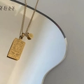 Close-up of gold Leo zodiac square pendant necklace with lion engraving on display card - Leo