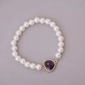 Elegant white pearl bracelet with a deep purple heart gemstone and gold frame detail - Purple