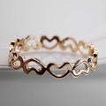 Detailed close-up of a hollow heart-shaped napkin ring with a rose gold metallic finish - Rose Gold