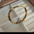 Pulsera de cuentas ojo de tigre con detalles dorados en un joyero de madera elegante - Pulsera de Ojo de Tigre