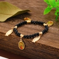 Macro shot of Virgin Mary pendants on black beaded religious bracelet over wood - Black (11394)