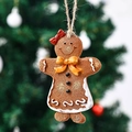 Close-up of resin gingerbread man ornament with red bow on a festive Christmas tree - Yellow Bow Style