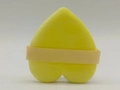 Macro shot of heart-shaped yellow cosmetic powder puff with satin ribbon handle - Yellow