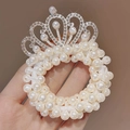 Elastico per capelli con corona di perle e strass scintillanti tenuto in mano - Piccola Corona di Perle