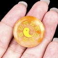 Yellow onyx round pendant with golden Yin Yang Tai Chi symbol held in hand - Topaz