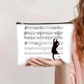 Détail d'une trousse à maquillage en toile avec imprimé notes de musique et zip noir - Chat Noir Grimpant sur des Notes (jiaying0018)