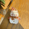 Close-up of a glittery acrylic snowman hair clip on a natural wooden tabletop - Smiling Snowman
